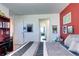 Bright bedroom with a red accent wall, neutral carpet, and view of the hallway entrance at 13437 Starhawk Ln, Parker, CO 80134