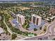 Aerial view of two condominium buildings with trees, parking, and a lake nearby at 7877 E Mississippi Ave # 208, Denver, CO 80247