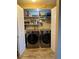 Convenient laundry closet features a modern washer and dryer set with ample shelving for storage at 7877 E Mississippi Ave # 208, Denver, CO 80247