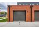A spacious garage exterior featuring a dark gray garage door and red brick wall at 115 W 2Nd Ave # 101, Denver, CO 80223