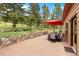 Outdoor patio features stone accent wall, dining table, and views of the backyard with mature trees at 187 Marion Dr, Evergreen, CO 80439