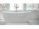 Close-up of a freestanding white bathtub with chrome fixtures and natural light from the windows at 1117 S Madison St, Denver, CO 80210