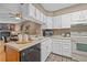 Traditional kitchen with white cabinets, tile floors, stone fireplace and adjacent dining area at 10567 Dartmouth, Lakewood, CO 80227