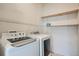 Functional laundry room equipped with a washer, dryer, and shelving units for storage at 7440 S Blackhawk St # 4-102, Englewood, CO 80112