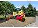 Colorful community playground with slides and climbing structure surrounded by mature trees and wood chip ground cover at 9963 E Carolina Cir # 104, Aurora, CO 80247