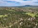 Scenic aerial of the community featuring a golf course, hills, and trees at 5846 S Pike Dr, Larkspur, CO 80118