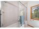 Tiled shower and bathtub with glass shower door, neutral color palette, and bright window at 5846 S Pike Dr, Larkspur, CO 80118