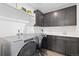 A laundry room with gray cabinets, white walls, and side-by-side stainless steel washer and dryer at 17851 Herrera Dr, Parker, CO 80134