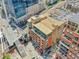 Excellent aerial view of a red brick building with spacious outdoor patios near a pedestrian bridge and modern office buildings at 2100 16Th St # 204, Denver, CO 80202