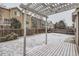 Snowy backyard featuring a pergola-covered deck and fence providing privacy, set against neighboring homes at 560 Hampstead Ave, Castle Rock, CO 80104