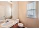 Neutral-toned bathroom features a toilet, vanity, sink, mirror, and window at 560 Hampstead Ave, Castle Rock, CO 80104