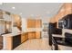 Open kitchen with wooden cabinets, tiled floors, black appliances, and adjacent dining area at 560 Hampstead Ave, Castle Rock, CO 80104