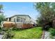 Inviting backyard with a wooden deck, lush green lawn, mature trees, and manicured garden beds at 4707 N Bearlily Way, Castle Rock, CO 80109
