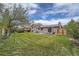 Well-maintained backyard with green grass, mature trees, and a concrete patio at 1641 S Parfet Ct, Denver, CO 80232