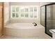 Luxurious soaking tub with tile surround and plantation shutters for privacy and natural light at 3231 Oak St, Wheat Ridge, CO 80033