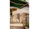 View of brick patio with iron railing, awning, outdoor furniture, and landscaping at 3231 Oak St, Wheat Ridge, CO 80033