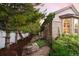 Scenic side yard with mature pine trees, mulch, rocks, and brick accents on the home's exterior at 3231 Oak St, Wheat Ridge, CO 80033