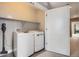 A well-equipped laundry room featuring a washer, dryer, and storage shelf at 4457 Wyandot St, Denver, CO 80211
