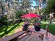 Inviting backyard patio with lush trees, planters, seating, and a red umbrella, perfect for outdoor entertaining at 19850 Indian Summer Ln, Monument, CO 80132