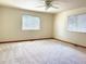 Bright bedroom with neutral carpet, two windows, and ceiling fan, providing comfortable space at 19850 Indian Summer Ln, Monument, CO 80132