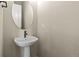 Stylish half bathroom with a pedestal sink and round mirror at 5909 S Platte Canyon Dr, Littleton, CO 80123