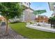 Landscaped backyard with artificial turf, rock border, patio with picnic table, and string lights overhead at 10254 Worchester St, Commerce City, CO 80022