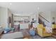 Open living space boasts hardwood floors, white kitchen, and comfortable yellow accent chair near the staircase at 24432 E Tennessee Pl, Aurora, CO 80018