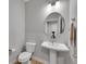 Compact powder room with a pedestal sink, oval mirror, modern lighting, and a white toilet at 6211 W 28Th Ct, Wheat Ridge, CO 80214