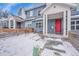 Blue townhome featuring a red front door, white trim, and a snowy yard with wooden fence at 6211 W 28Th Ct, Wheat Ridge, CO 80214