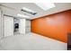 Large room with neutral carpet, bright lighting, and an orange accent wall at 9674 Fox Den Dr, Littleton, CO 80125