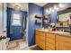 Well-lit bathroom with blue walls, double vanity, framed mirror, and shower with a patterned curtain at 5770 Waverley Ave, Firestone, CO 80504
