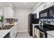 Well-lit kitchen with white cabinets, stainless steel appliances, and stone backsplash at 7468 S Alkire St # 204, Littleton, CO 80127