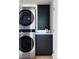 Modern laundry room with stacked washer and dryer and sleek black storage and accent wall at 199 S Ivy St, Denver, CO 80224