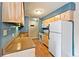 Galley kitchen with light blue walls, wood cabinets, and white appliances at 7335 E Quincy Ave # 303, Denver, CO 80237