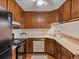 Galley kitchen featuring wood cabinets, neutral countertops, and essential appliances at 3470 S Poplar St. # 110, Denver, CO 80224