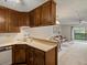 Galley kitchen showcasing wood cabinetry, a breakfast bar, and an open flow to living space at 3470 S Poplar St. # 110, Denver, CO 80224