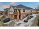 Exterior view of a two-story home with a brick foundation, a wooden balcony, and snowy landscaping at 7560 S Biloxi Ct, Aurora, CO 80016