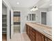 Bright bathroom with dual vanity, neutral tile floors, and a glimpse into the adjacent bedroom at 7560 S Biloxi Ct, Aurora, CO 80016