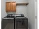 Functional laundry room with modern washer and dryer units and upper cabinets at 7560 S Biloxi Ct, Aurora, CO 80016