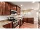 Charming kitchen features stainless steel appliances, granite countertops, wood floors, and ample natural light at 7580 S Biloxi Ct, Aurora, CO 80016