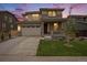 Attractive two-story home with stone accents and a front porch, beautifully illuminated at twilight at 14818 Dahlia St, Thornton, CO 80602
