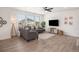 Cozy living area featuring wood floors, a comfortable gray sofa, and large windows providing natural light at 14818 Dahlia St, Thornton, CO 80602