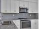 Kitchen with white cabinets, gray subway tile backsplash, and gray countertops at 413 N De Gaulle Ct, Aurora, CO 80018