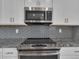 Kitchen with a range and microwave oven with gray subway tile backsplash and gray countertops at 413 N De Gaulle Ct, Aurora, CO 80018