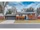 Charming front exterior with brick and wood siding, a blue door, and solar panels at 2641 S Magnolia St, Denver, CO 80224