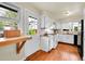 Bright kitchen features white cabinetry, an eat-in nook, white appliances and wood floors at 1241 Wabash St, Denver, CO 80220