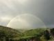 Dramatic landscape featuring a vibrant double rainbow arcing over rolling green hills and valleys at 6057 Red Hill Rd, Boulder, CO 80302