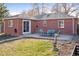 A brick home with a patio and furniture is centered on a green lawn at 1580 Quince St, Denver, CO 80220