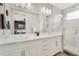 Bright bathroom featuring a double sink vanity with a large mirror, marble tile, and a glass shower enclosure at 8982 Delacorte St, Littleton, CO 80129