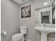 Stylish half bathroom with modern fixtures, a pedestal sink, and a unique decorative painting at 8982 Delacorte St, Littleton, CO 80129
